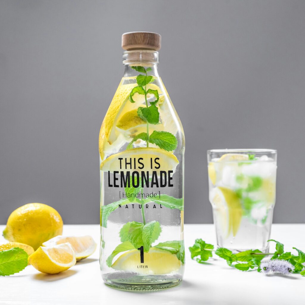 Glass bottle of lemonade with mint and lemon slices for a fresh, natural drink.